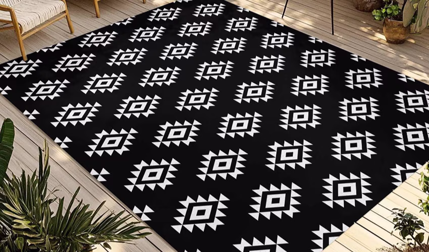 Black outdoor rug with a small white pattern on a wooden deck