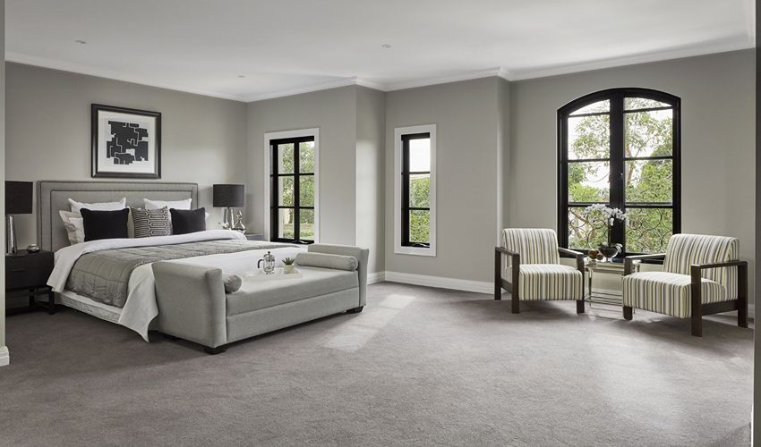 Grey wall-to-wall carpet between two beds under a window